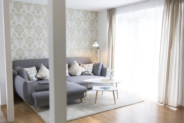 Villa Maare - Einblick ins Wohnzimmer der gleichnamigen Maisonette-Ferienwohnung mit großem Sofa und Beistelltischchen