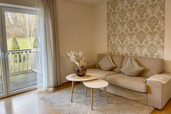 Villa Maare - Wohnzimmer der gleichnamigen Ferienwohnung mit gemütlichem Sofa und Blick nach draußen