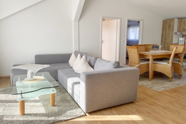 Villa Maare - Einblick in Ferienwohnung Holzmaar mit gemütlichem Sofa, Küchenzeile und Esstisch mit sechs Stühlen